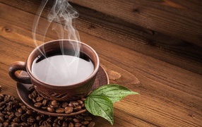 Чашка горячего кофе с зернами на деревянном столе