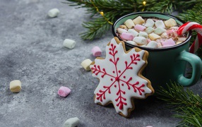 A cup of hot drink with marshmallows on the table with cookies
