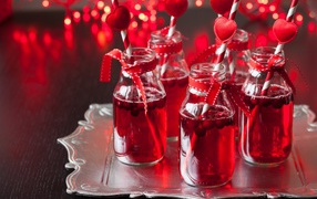 A delicious drink with cranberries in glass bottles on a table with straws