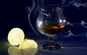 A glass of cognac in smoke with slices of lemon