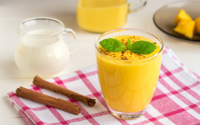 A glass of juice on a table with milk and cinnamon