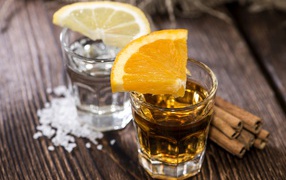 Рюмка водки и рюмка виски на столе с кусочками лимона