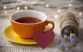 Большая чашка чая на столе с розовым бумажным сердцем и цветами