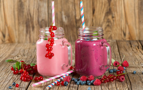 Berry smoothies in jars on a table with fresh berries of raspberries, currants and blueberries