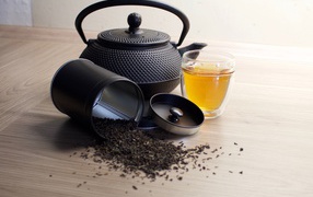 Черный чай на столе с чайником и чашкой