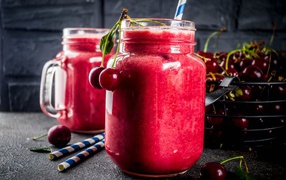 Вишневое смузи в стеклянной банке на столе с ягодами