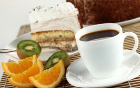 Coffee with a piece of cake and slices of orange and kiwi on the table