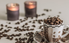 Cup with coffee beans on a table with candles