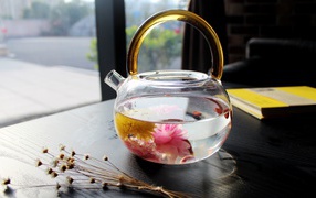 Flower tea in a glass teapot on the table