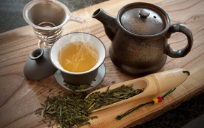 Fresh hot tea on the table with tea leaves and a kettle