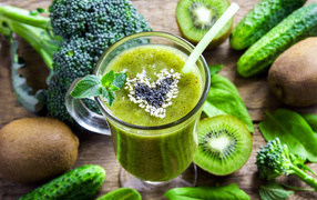 Glass of green smoothies on a table with kiwi, cucumber and broccoli