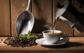 Горячий кофе наливают в чашку на столе с кофейными зернами