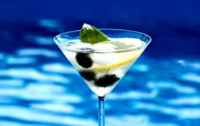 Martini in a glass with lemon and olives