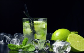 Mojito cocktail on a black background with lime and ice cubes