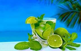 Mojito in a glass with fresh mint and lime on a tropical beach