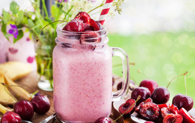 Smoothies in a bottle with a straw and a sweet cherry