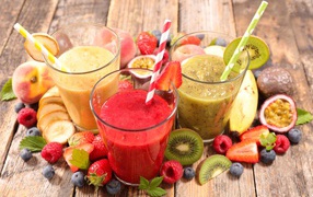 Smoothies in glasses with straws on the table with fresh fruit
