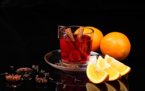 Tea with cinnamon and slices of orange on a black background
