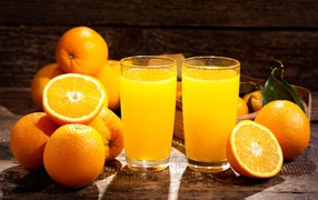 Two glasses of fresh orange juice on a table with fruit