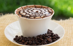 White cup of cappuccino with a pattern on the skin with coffee beans