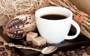 Белая чашка кофе с зернами и кусочками сахара на столе 