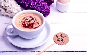 Белая чашка кофе с цветами сирени и яйцом на завтрак