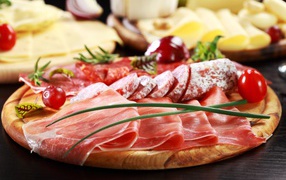 Аппетитная мясная нарезка на деревянной доске с зеленым луком