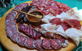 Appetizing cold cuts on the cutting board with honey