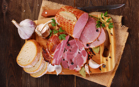 Appetizing ham, garlic and slices of bread on a cutting board