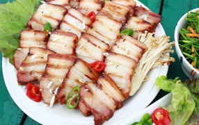 Аппетитное копченое сало на столе с овощами