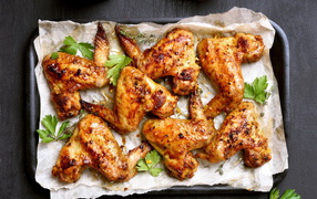 Baked chicken wings on a baking sheet with spices and herbs