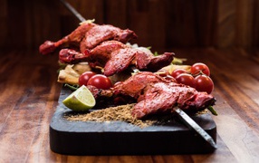 Курица жареная на шампурах на столе с овощами 