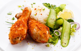 Chicken legs with rice and salad on a white plate