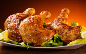 Жареные куриные окорочка на зеленых листьях салата 