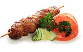 Шашлык с огурцами, помидорами и зеленью на белом фоне