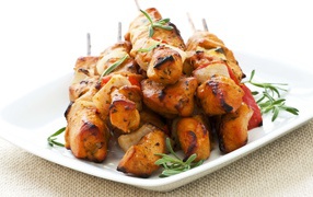 Шашлыки на белой тарелке с зеленью розмарина