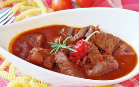 Meat goulash in a white plate with hot pepper