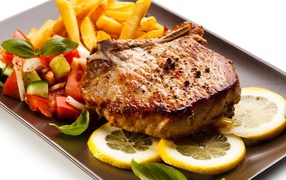 Meat with french fries, salad and lemon slices