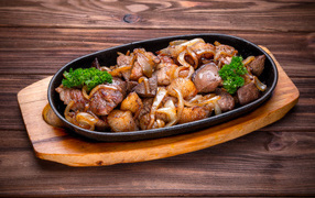 Pieces of shish kebab with onion and parsley in a frying pan