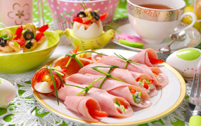Рулетики из ветчины и фаршированные яйца на тарелке