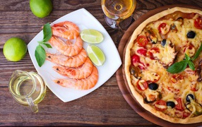 Appetizing pizza on a table with shrimps and pieces of lime