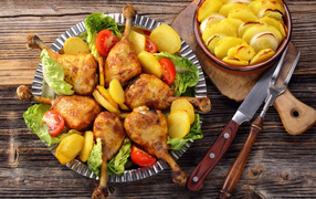Baked chicken legs with fried potatoes on the table