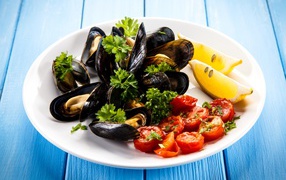 Mussels with tomatoes, slices of lemon and parsley on a white plate