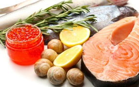 Красная рыба с улитками и красной икрой на столе с лимоном и базиликом