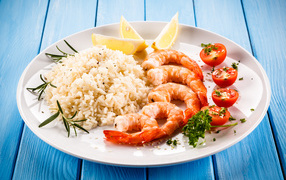 Shrimp on a plate with rice, tomato and lemon