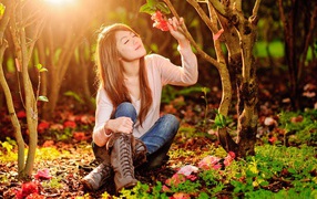 Девушка сидит на земле под ярким солнцем в лесу