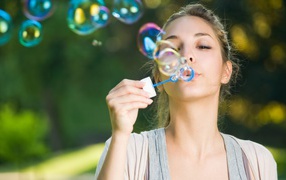 Милая молодая девушка пускает мыльные пузыри