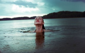 A young girl is bathing in a lake