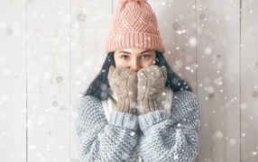 Молодая девушка с теплом свитере с шапкой на голове и перчатках