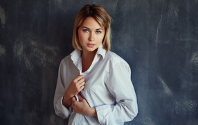 Красивая девушка блондинка в белой рубашке у стены 